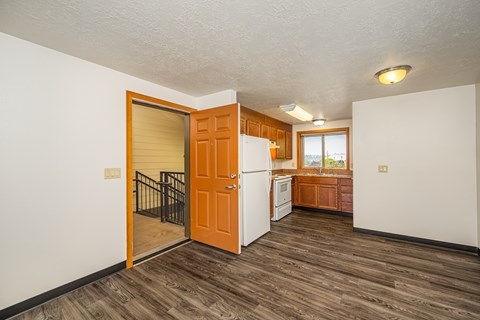 A kitchen with a white fridge and wooden floors.