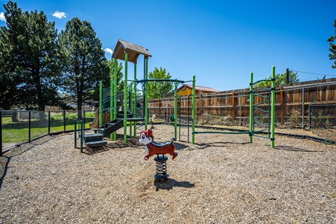 A playground with a green swing set and a red slide.