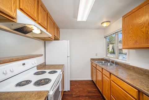 A kitchen with a white stove and wooden cabinets.