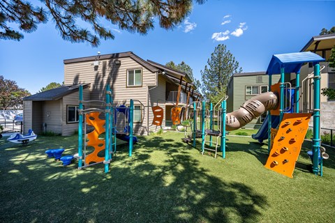 A playground with a slide and climbing structures in front of a house.