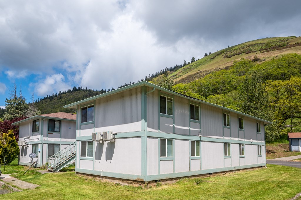a white and blue house with a mountain in the background