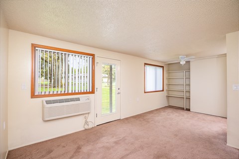an empty living room with a window and a door to a closet