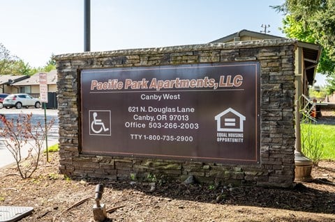 a sign for pacific park apartments llc in front of a stone building
