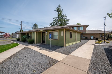 a green house with a sidewalk in front of it