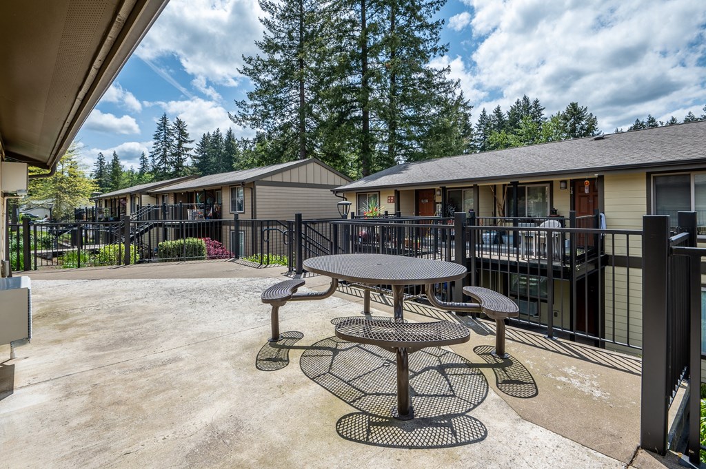 a patio with a table and chairs in front of a building