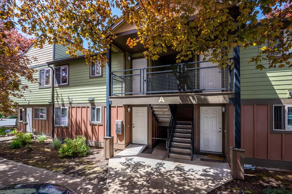 front view of a green house with stairs and a balcony
