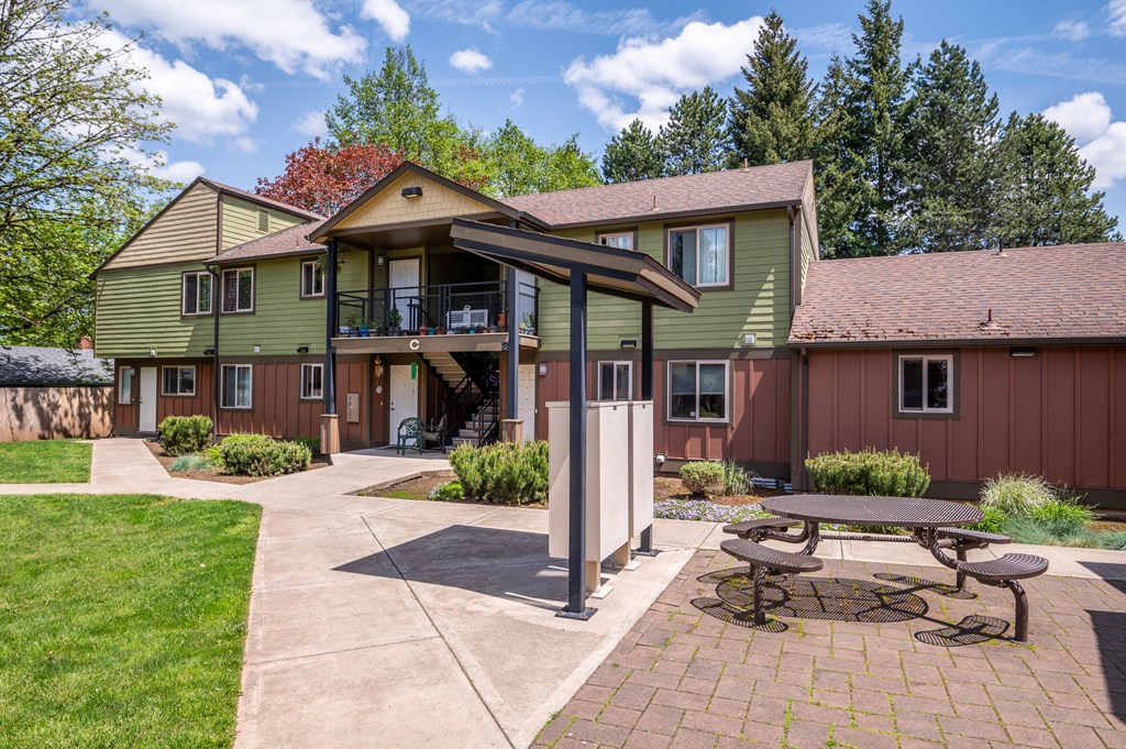 a patio with a picnic table in front of a house