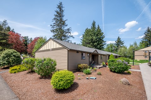 a small house with a gravel driveway and a landscaped yard