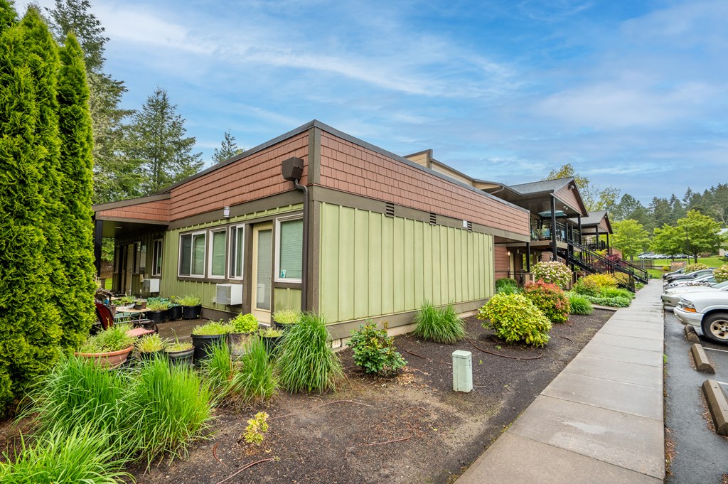 a green house with a sidewalk and plants in front of it
