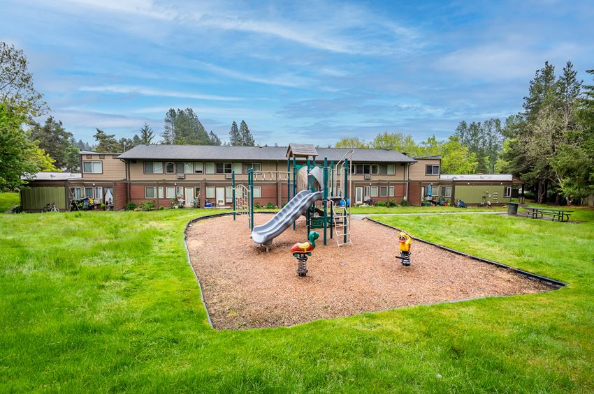 a playground with a large slide in front of a building
