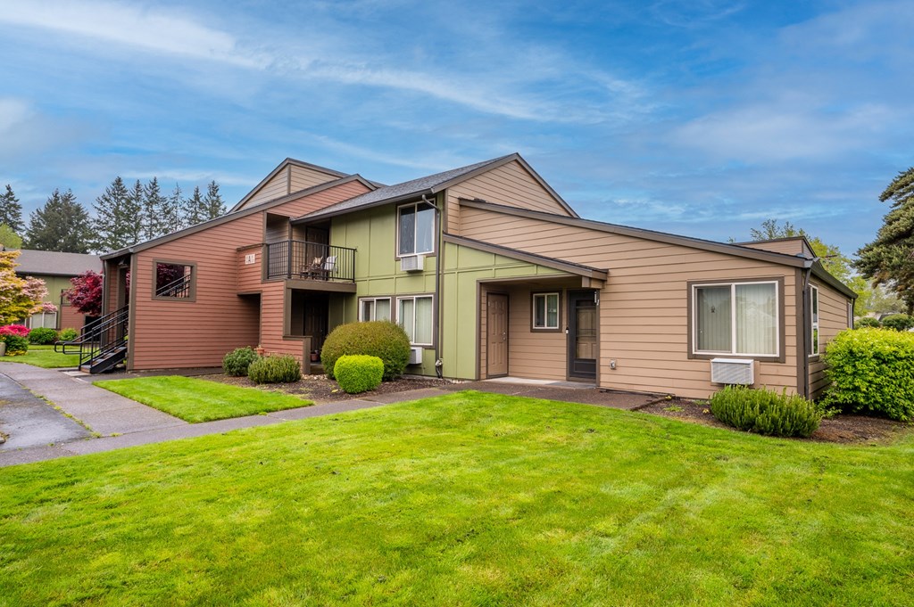 the front of a house with a green lawn and a sidewalk