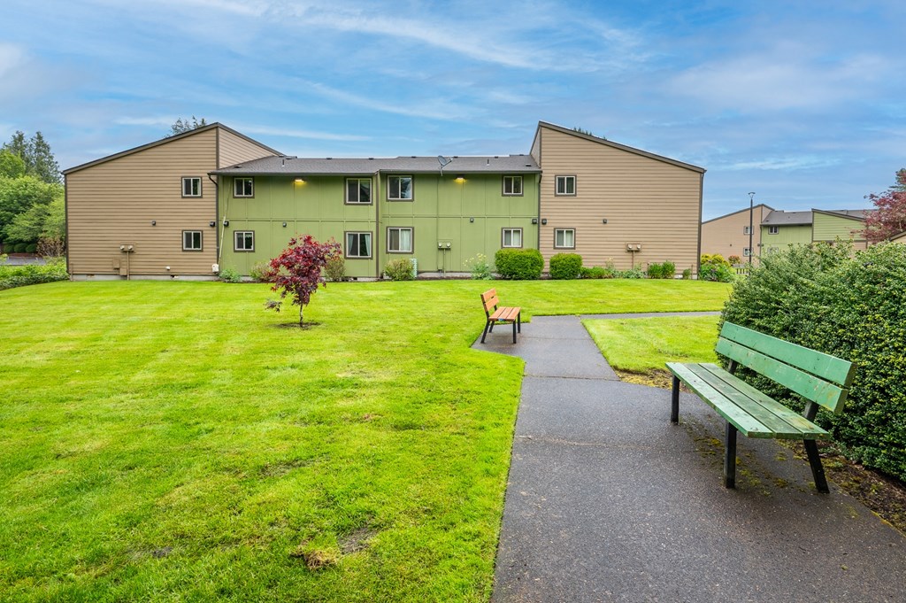a park with two benches and a building in the background