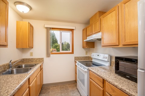 a kitchen with granite counter tops and wooden cabinets and a window