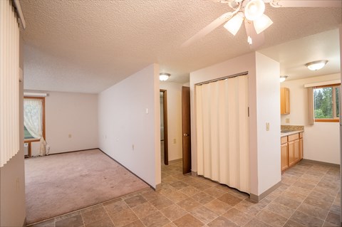 the living room and dining room of an empty house with a ceiling fan