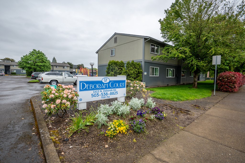 a sign in front of an apartment building with flowers