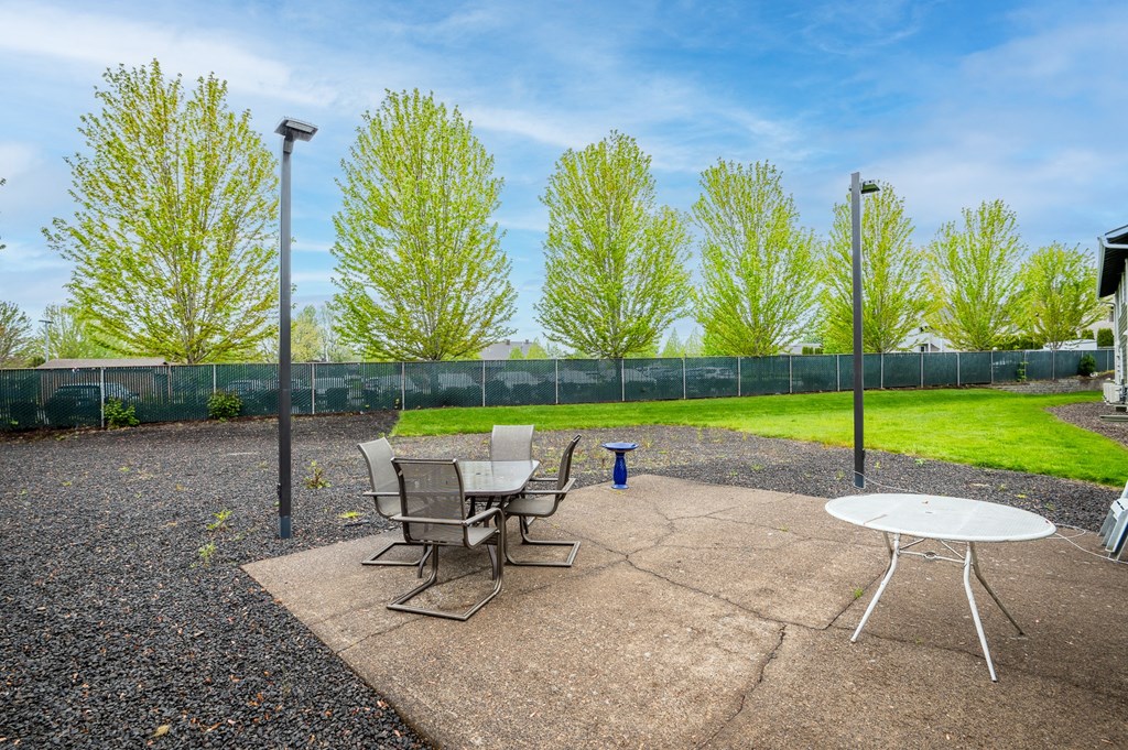a patio with a table and chairs in front of a fence