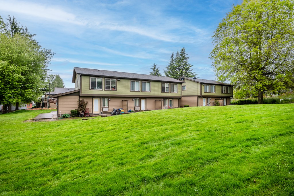 a large house on a grassy hill with trees