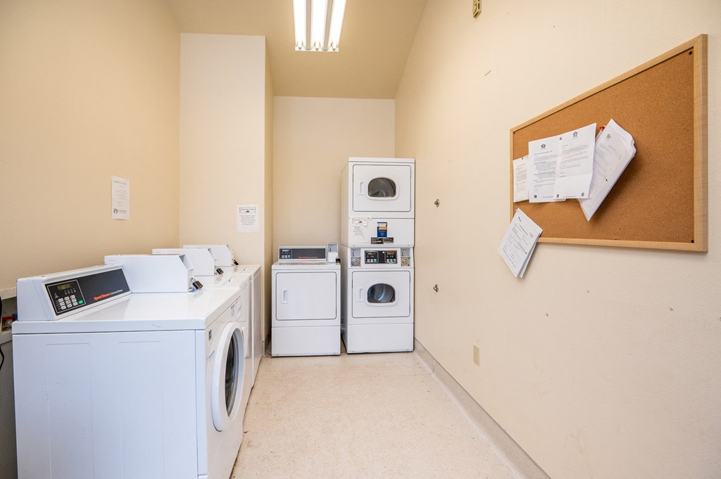 a laundry room with washes and dryers and a bulletin board