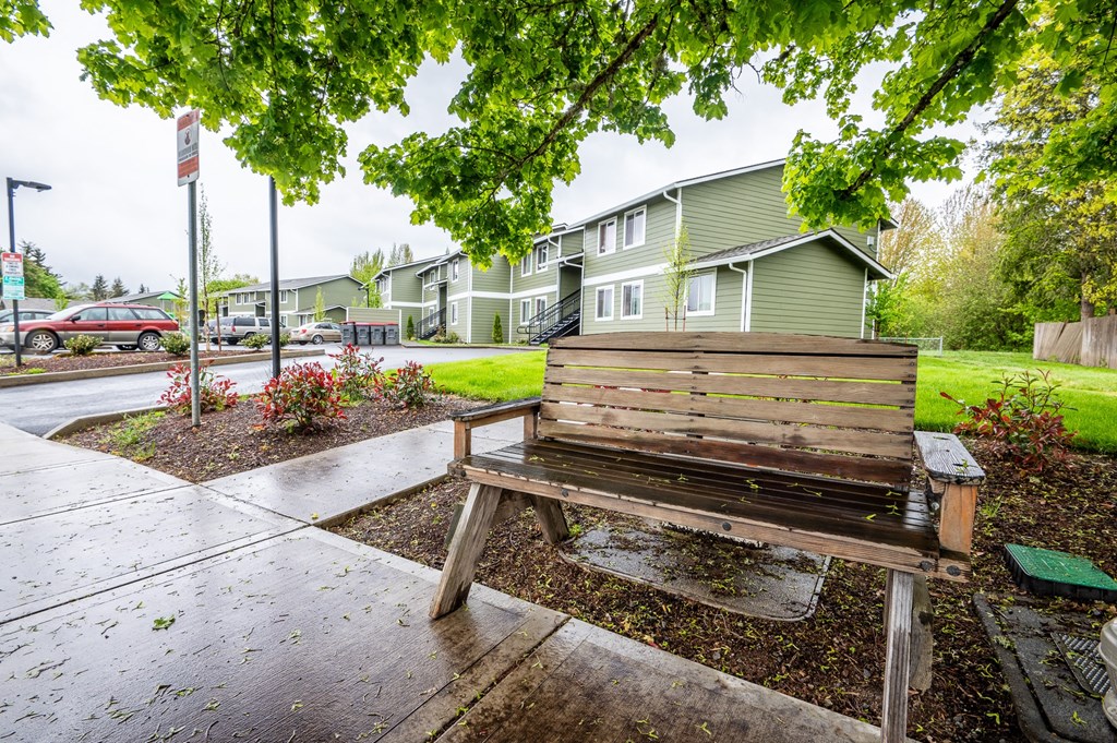 a wooden bench sitting under a tree in front of some houses