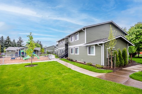 a gray house with a yard and sidewalk in front of it