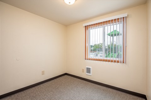 a living room with a large window and a carpeted floor