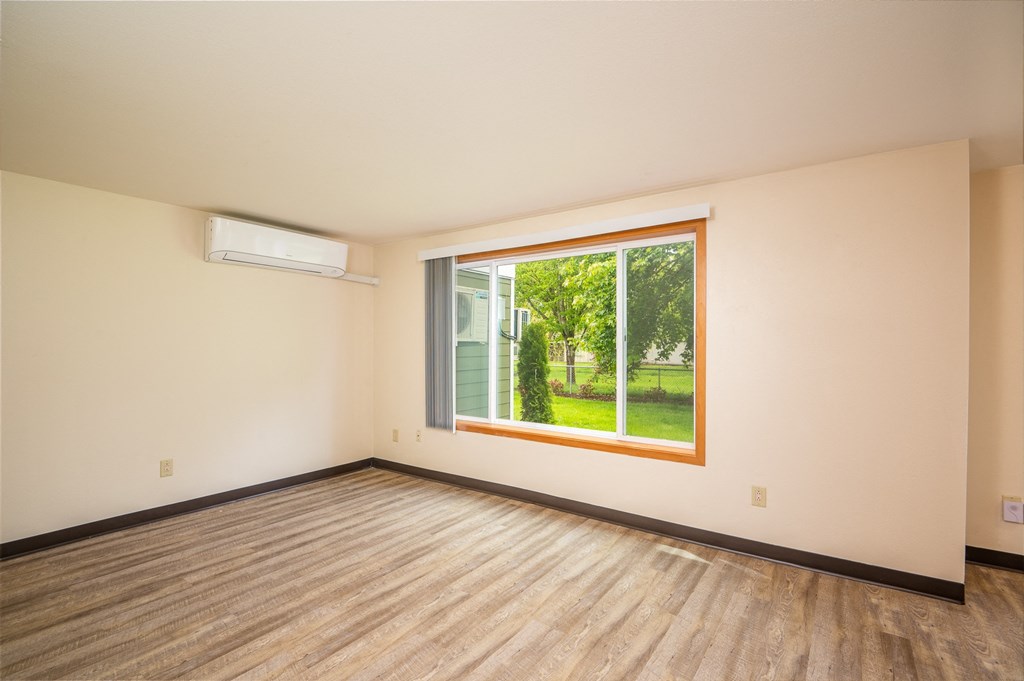 an empty living room with a large window and wooden floors