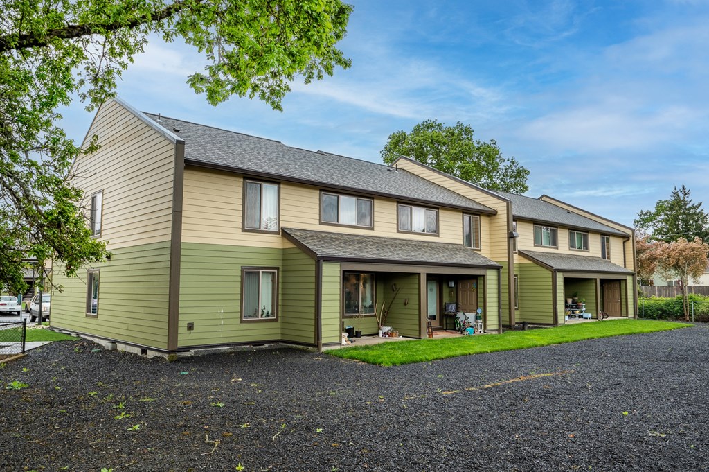 a green and yellow house with a gravel driveway