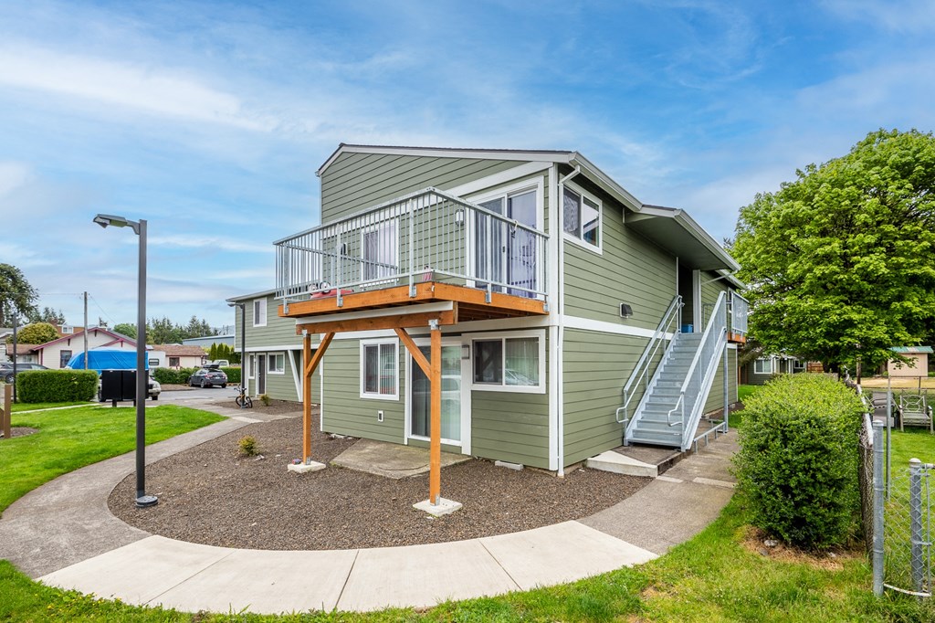 a green house with a wooden deck and stairs