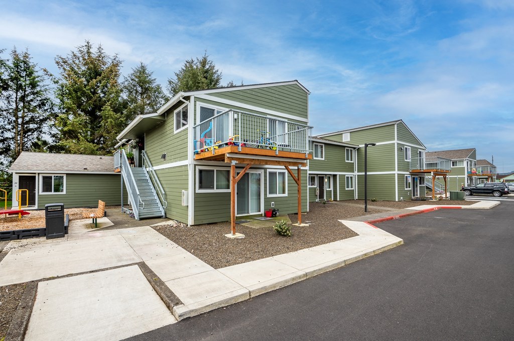 a row of green manufactured homes with a porch and stairs