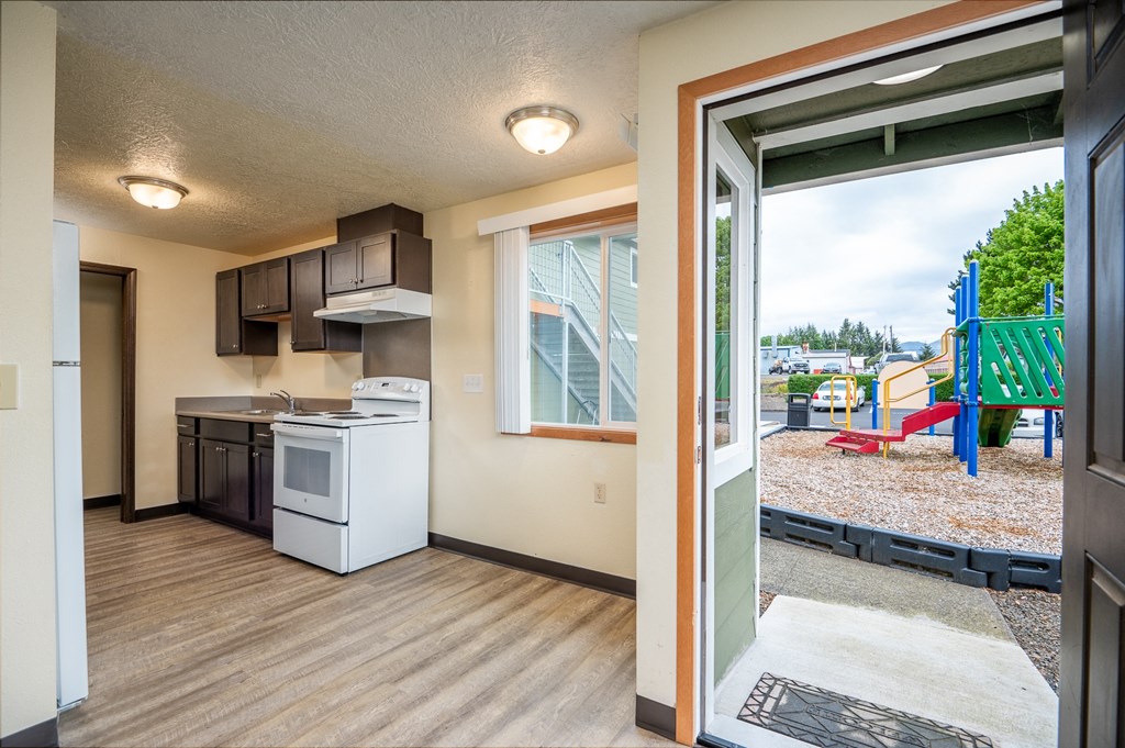 an open door leading into a kitchen with a view of a playground and a yard