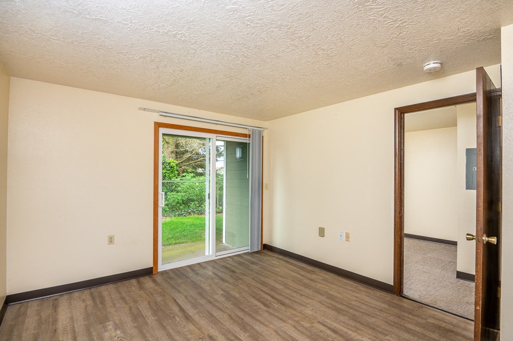 the living room of an empty house with a door to the backyard