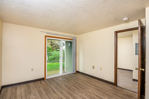 the living room of an empty house with a door to the backyard