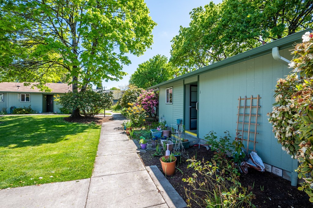 the side of a blue house with a sidewalk in front of it
