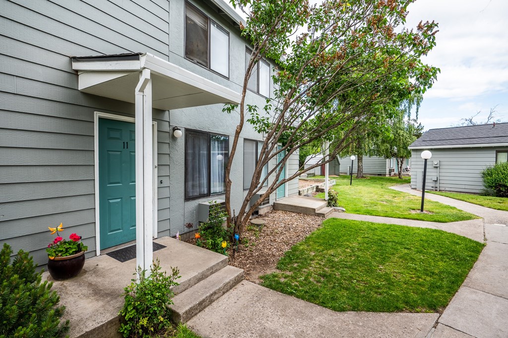 the front of a gray house with a green door