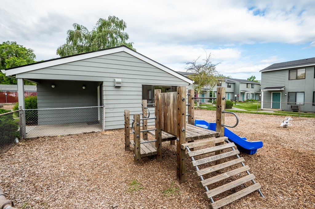 the backyard of a house with a playground and a swing set