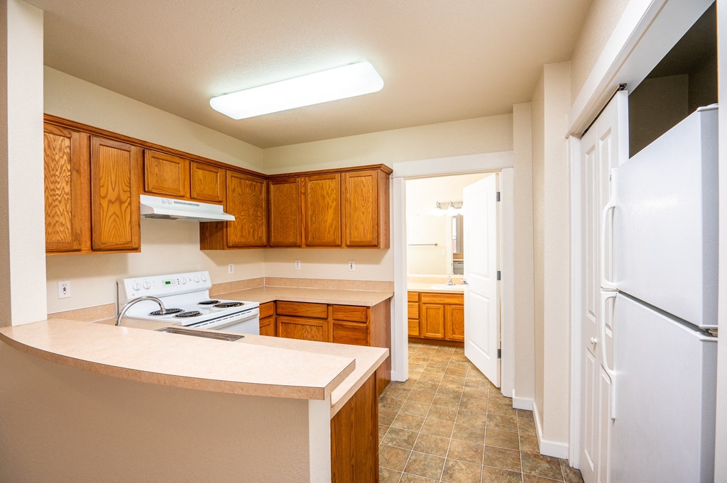 a kitchen with wooden cabinets and a white stove and refrigerator