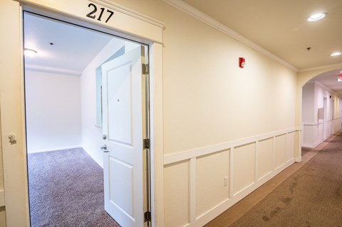 a hallway with a door to a room and an exit sign on the wall