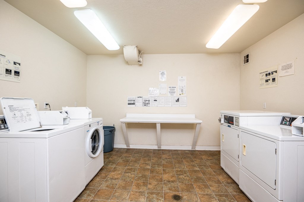 a laundry room with washes and dryers and a table with a counter