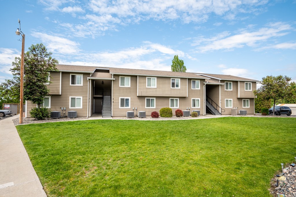 the view of an apartment building with a green lawn
