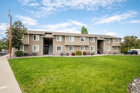 the view of an apartment building with a green lawn