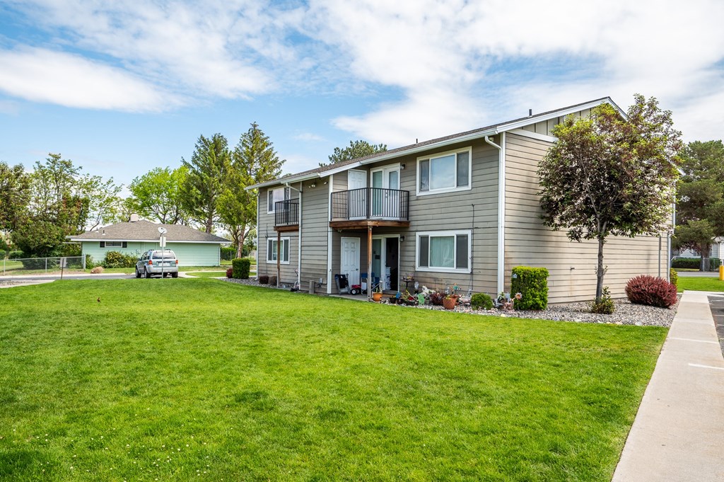 a gray house with a green lawn in front of it