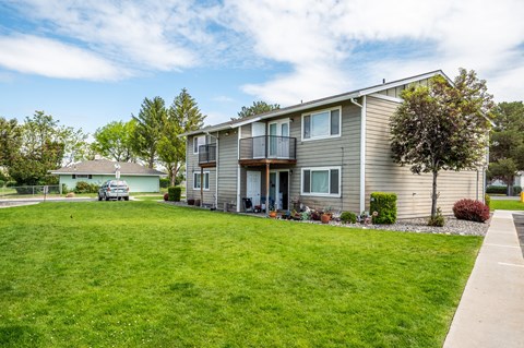 a gray house with a green lawn in front of it