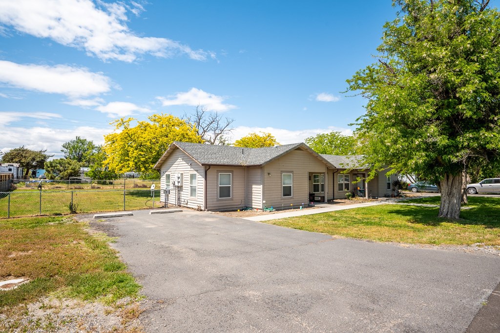 a small tan house with a road in front of it