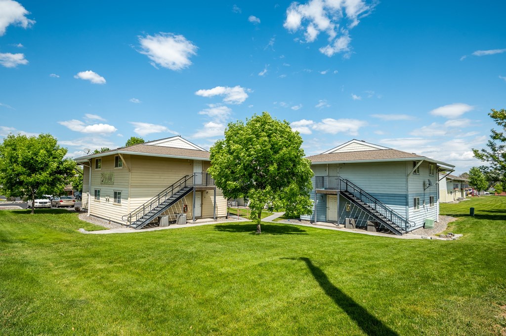 two houses on a green lawn with a blue sky