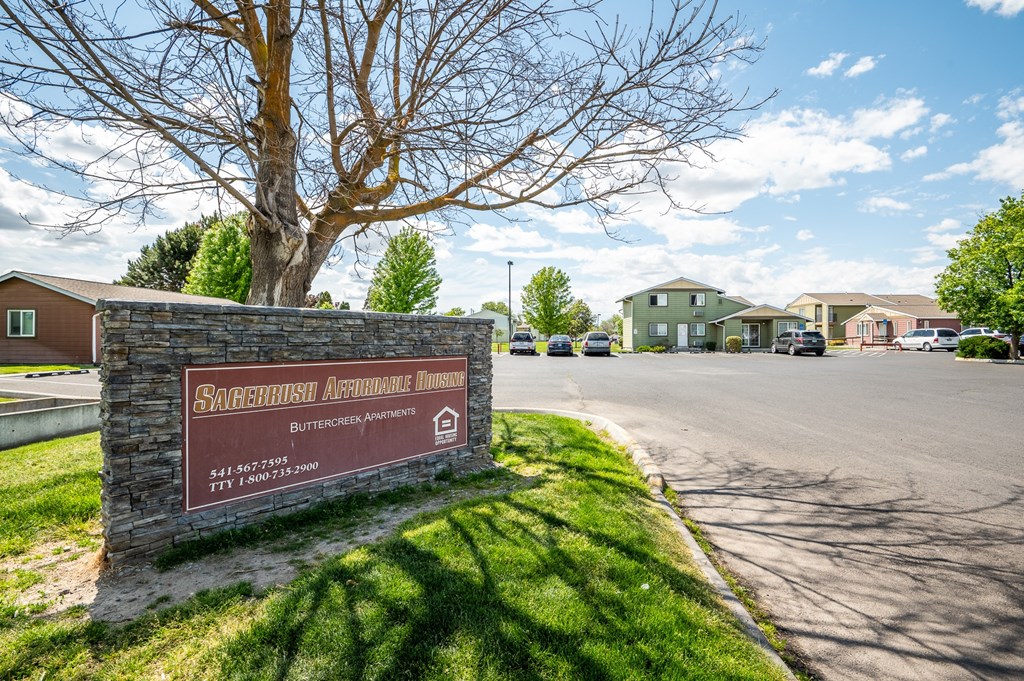 a brick sign sits on the side of a road in front of some houses