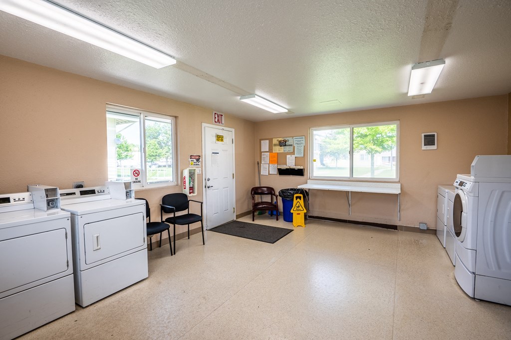 a laundry room with washers and dryers and a table with chairs