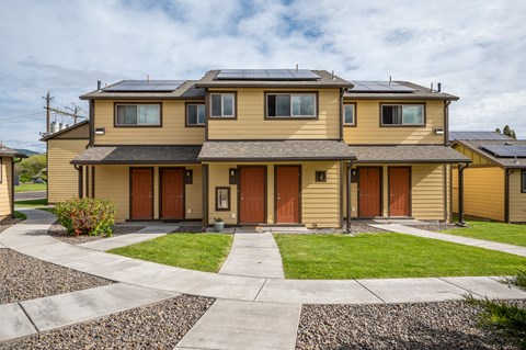the front of a yellow house with solar panels on the roof
