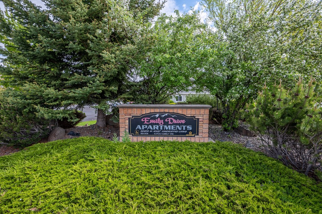 a sign for sandy dunes apartments in front of trees