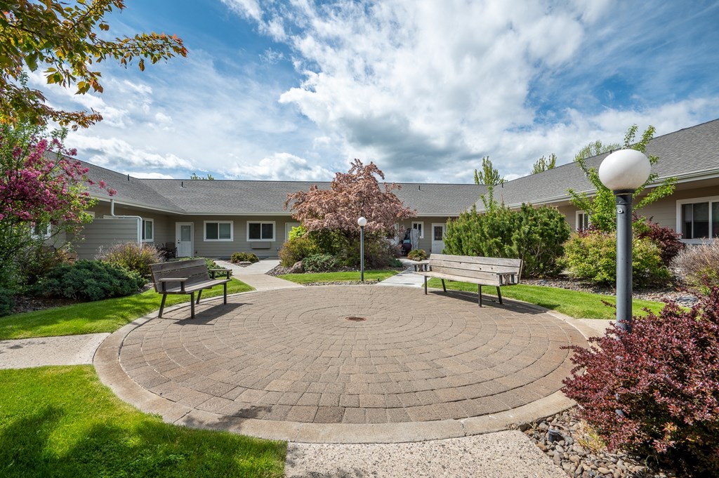 a circular brick patio with benches in front of a building