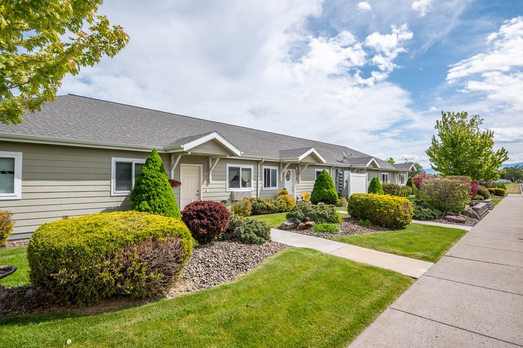 a home in a subdivision with a sidewalk and landscaping